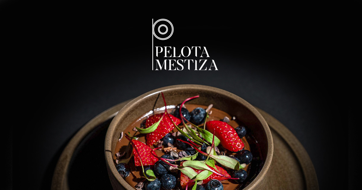 Logotipo de Pelota Mestiza sobre un postre de chocolate con fresas y moras